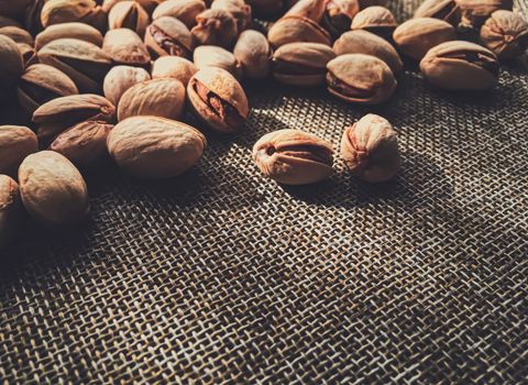 Pistachio nuts on rustic linen background, food and nutrition