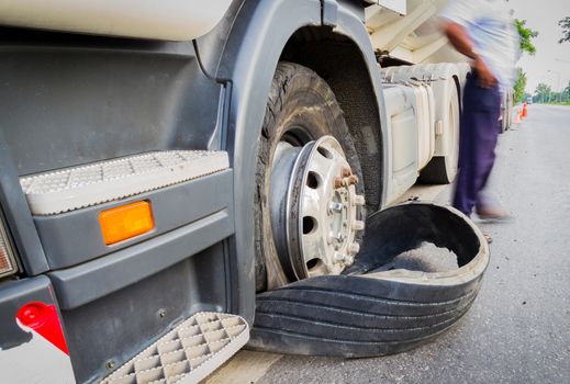 Damaged 18 wheeler semi truck burst tires by highway street, with blurred driver.