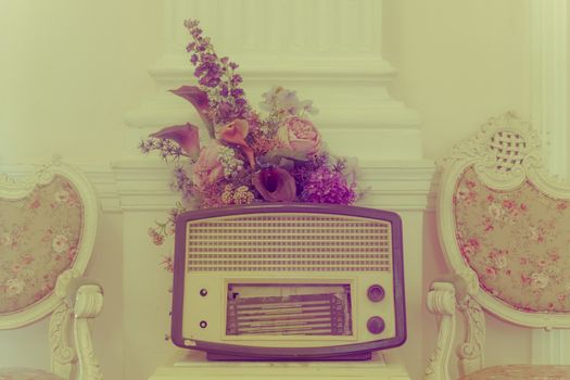 antique radio with flower and chairs on vintage background.