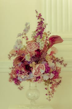 Bouquet flower in the vintage vase on the yellow background, vintage style.