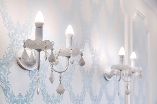Vintage candelabra with lamps on a beautiful wall with floral patterns