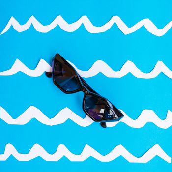 a pair of sunglasses float on a surface that represents the sea