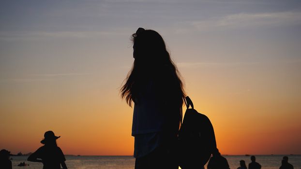 Side view of back light of a woman silhouette warm sunset in front of sun - tourist beach at sunset