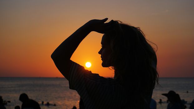 Side view of back light of a woman silhouette warm sunset in front of sun - tourist beach at sunset