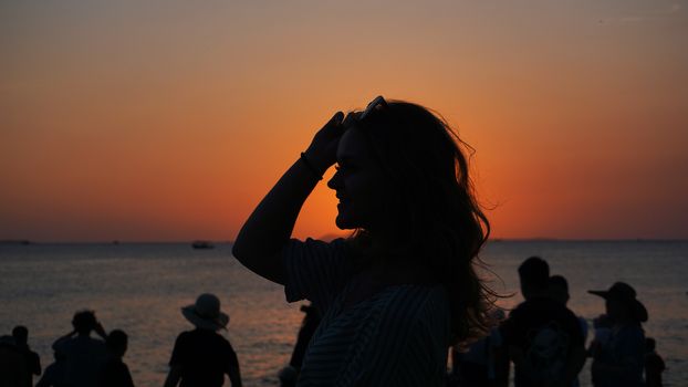 Side view of back light of a woman silhouette warm sunset in front of sun - tourist beach at sunset