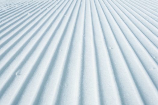 Geometry track lines on a ski slope left by a snowcat as a texture background.