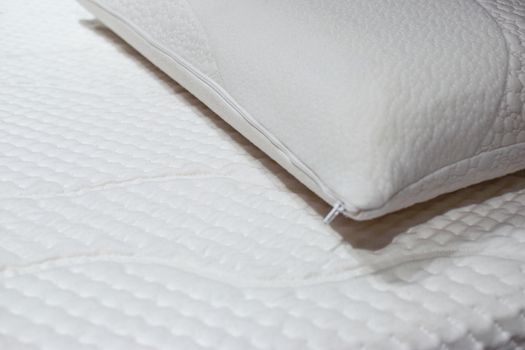 Modern and healthy bed with white mattress and pillow in close-up.