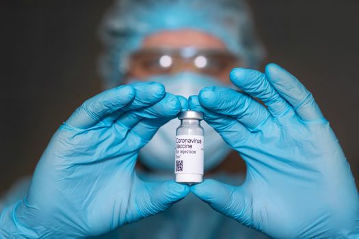 Coronavirus vaccine. Doctor with a vaccine. Hands holding a coronavirus vaccine ampoule, against Covid-19.