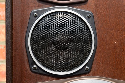 Mid-range speaker with a protective grid on the speaker.
