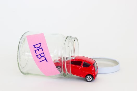horizontal photo of red car toy going into the glass bottle with the word DEBT on its pink label.