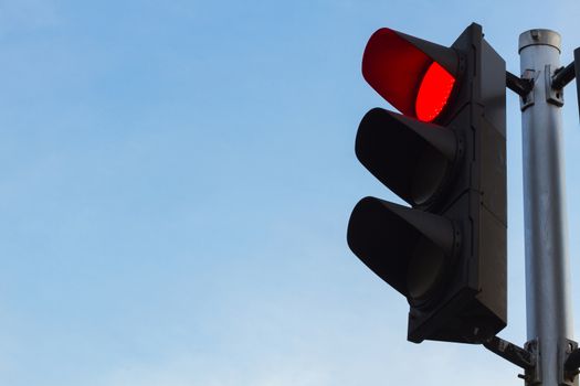 red color on the traffic light with a clear beautiful blue sky in background.