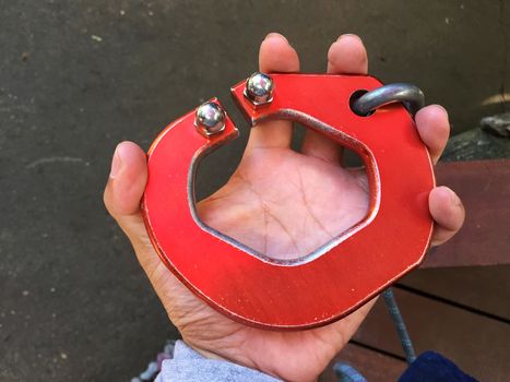 horizontal photo of big red carabiner on man's left hand