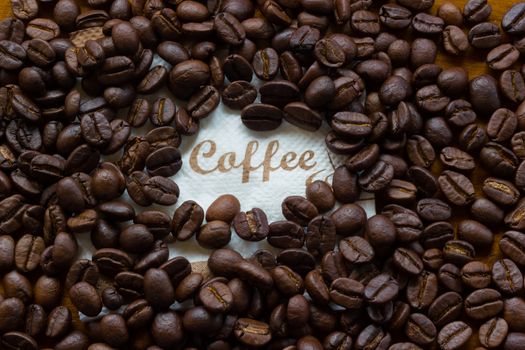 closeup of brown coffee beans background with word Coffee in the middle.