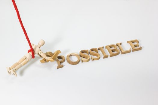 Changing the word impossible to possible with wooden dummy hanging on the red rope