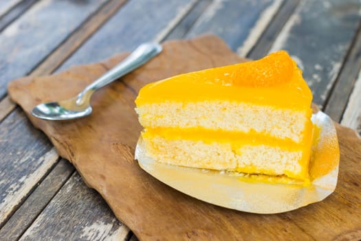 orange cake on wood dish with silver spoon, selective focus.