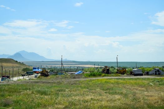 Old agricultural machinery stands in a village on a site with agricultural machinery