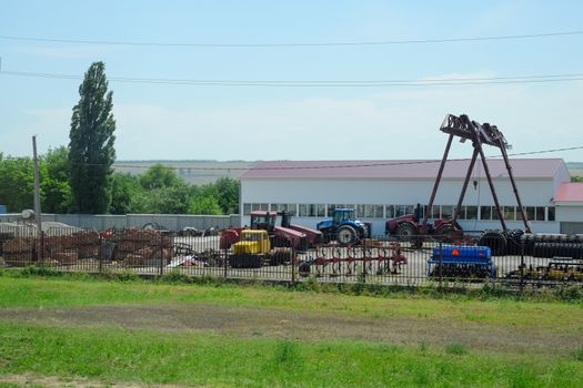 Old agricultural machinery stands in a village on a site with agricultural machinery