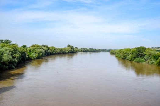 Passing over the bridge over the river. The landscape of the river, the surface and the trees of the river's waterplain.