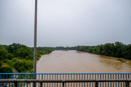 Passing over the bridge over the river. The landscape of the river, the surface and the trees of the river's waterplain.