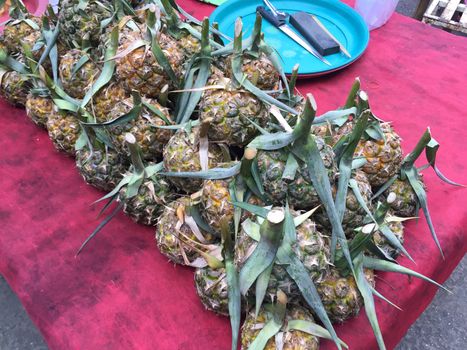 horizontal photo of pineapple sold in thai market.