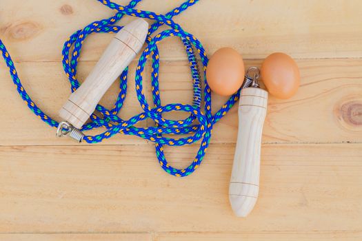 top view blue jump rope with two eggs on wooden bakcground, sex concept