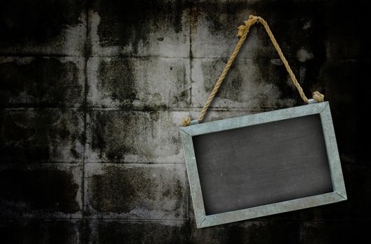 iron blackboard hanging on old grunge wall texture with vignette.