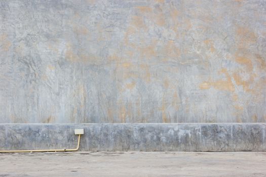 grungy mud dirty concrete wall background with yellow PVC pipe on the ground.