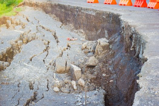 cracked road after earthquake with yellow barricade