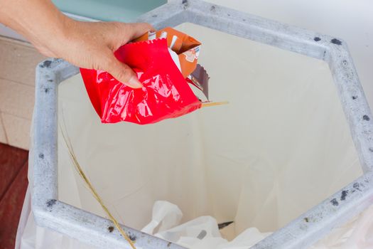 closeup hand throws away red waste material into trash container.