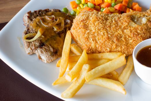 closeup grilled steak, fried chicken, french fries and vegetables on white dish.