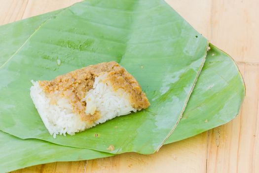 sticky rice and creamy  egg custard wrapped with banana leaf on wooden background, Thai dessert.