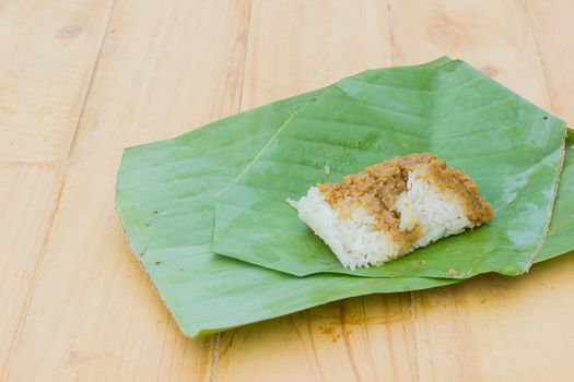 sticky rice and creamy  egg custard wrapped with banana leaf on wooden background, Thai dessert.
