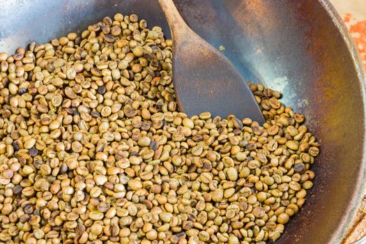 close up roasted coffee beans in a pan with wooden turner