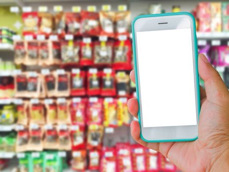right hand holding green blank screen mobile phone with supermarket blur background, online shopping concept.