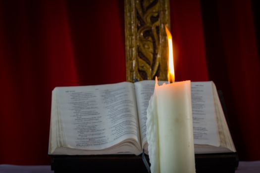 A bible open on a table next to a candle