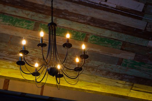 lighting bulbs on the chandelier hanging from the wooden ceiling. Copyspace