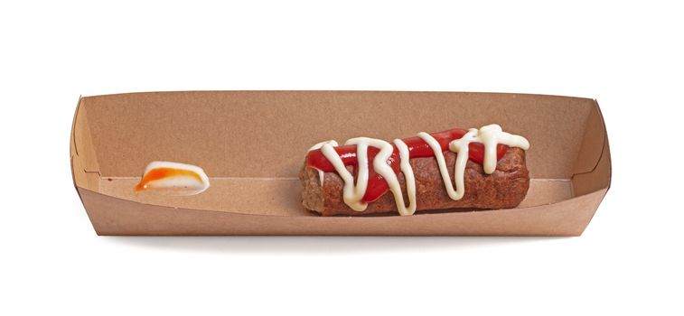 One frikadel with ketchup and mayonnaise, a Dutch fast food snack on a paper tray, half eaten