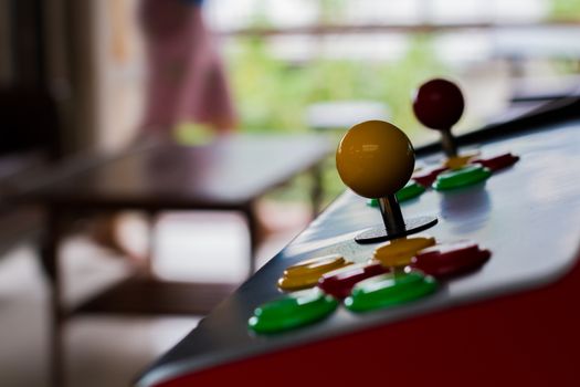 silhouette yellow joystick and six colorful button of an old arcade video game on blur background