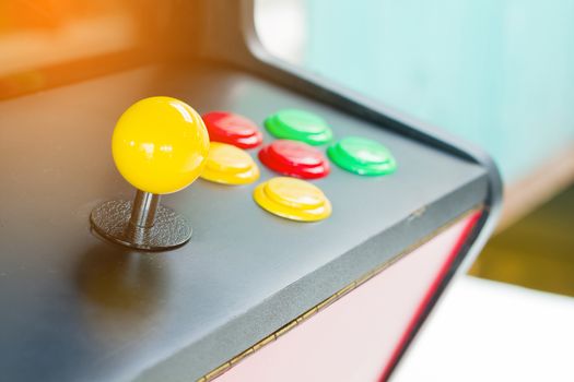 yellow joystick of an old arcade video game with six colorful button. Copyspace