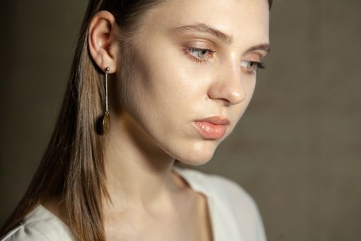 Portrait of beautiful fair young woman with fashion jewelry, one light source