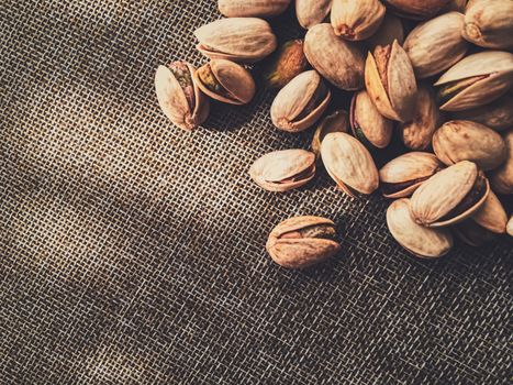 Pistachio nuts on rustic linen background, food and nutrition