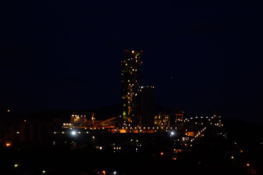 The building of a cement plant at night, the lights of a lamp lighting a factory. Industrial facility.