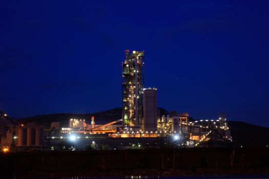 The building of a cement plant at night, the lights of a lamp lighting a factory. Industrial facility.