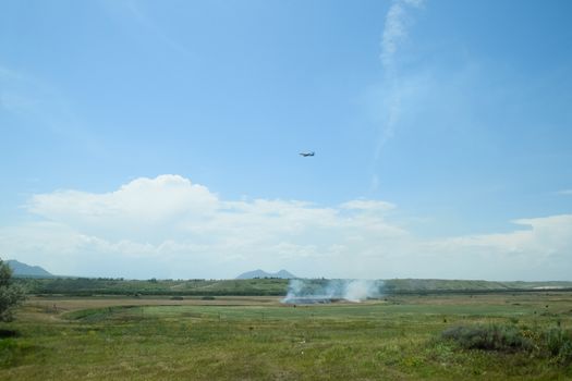 The plane sets up, flying over the field where the dry grass burns