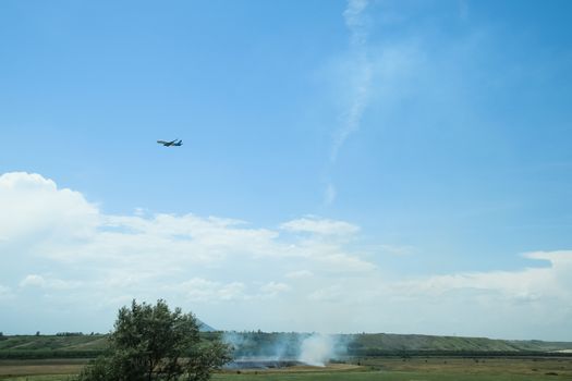 The plane sets up, flying over the field where the dry grass burns
