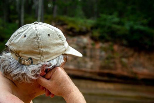 Man at the rock. Portrait of man at the rock,  on coast of the river. The man looks at the cliff. Rock on the Gauja river. Cliff is steep rock face, especially at the edge of the river or the sea.

