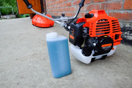 Prepared fuel mixture for a two stroke gasoline trimmer engine. Gasoline trimmer. Trimer gascosis with a leaf for mowing grass and shrubs.