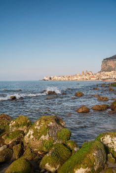 Idyllic view of Cefalu from the long sandy beach. Cathedral and Rocca di Cefalu rocky mountain on a sunny day in Cefalu, Sicily, Southern Italy.