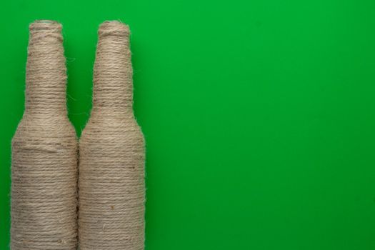 Two glass bottles of beer reused with hemp yarn on the left with a green background. Recycling and reusable concept