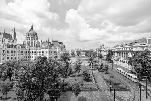 Hungarian parliament building from behind and yellow vintage tram passing by on a sunny day in summer season in Budapest, Hungary - aerial view.